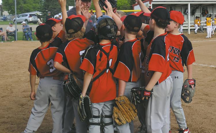 Coach Chase Boen brings the 10U team into a huddle before the start Thursdays game against Park River. Photo by Rebecca Davis