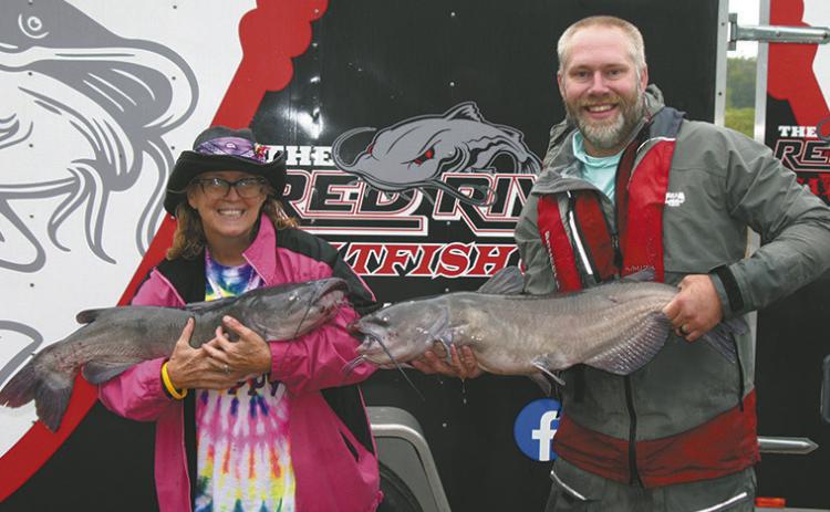 First-place winners May Thompson of East Grand Forks and Jayson Ackerson of West Fargo show off two of their Day 2 catches, weighing 18.83 and 16.41 pounds. The pair brought 41.31 pounds to the scales on Day 2 and finished the Drayton Catfish Capital Tournament with a winning two-day total of 76.68 pounds. Photo by Rob Boll